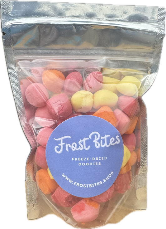 A transparent pouch of Frost Bites - Freeze Dried Goodies' "The Mini Star Blasts" freeze-dried candies in various shades of pink and orange, sealed and labeled with a blue logo, featuring mini star blasts.